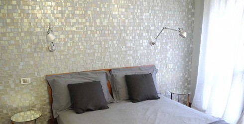 Pared de dormitorio decorada con papel pintado imitando un mosaico cerámico.